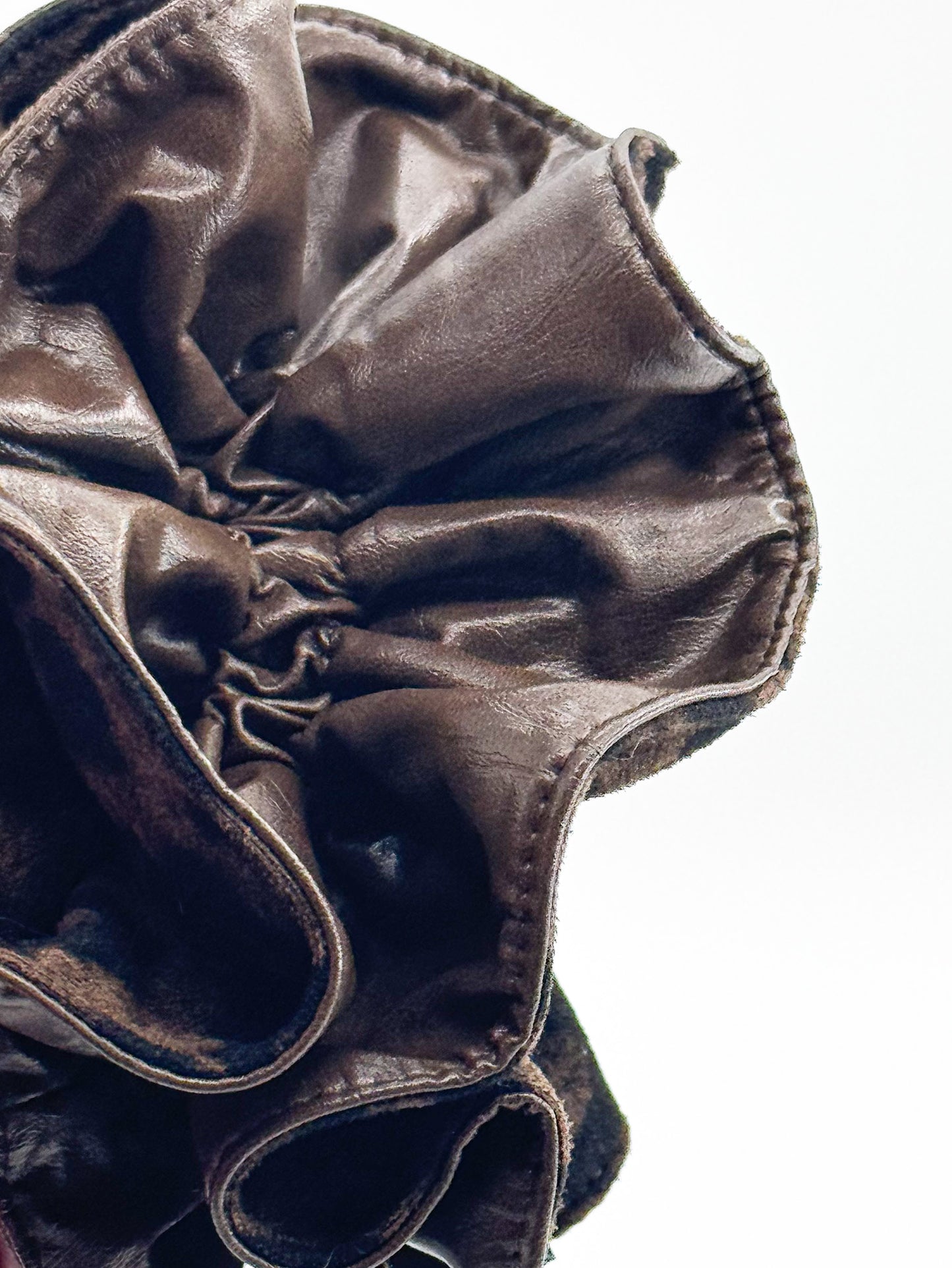 Close-up of a brown leather scrunchie on a white background