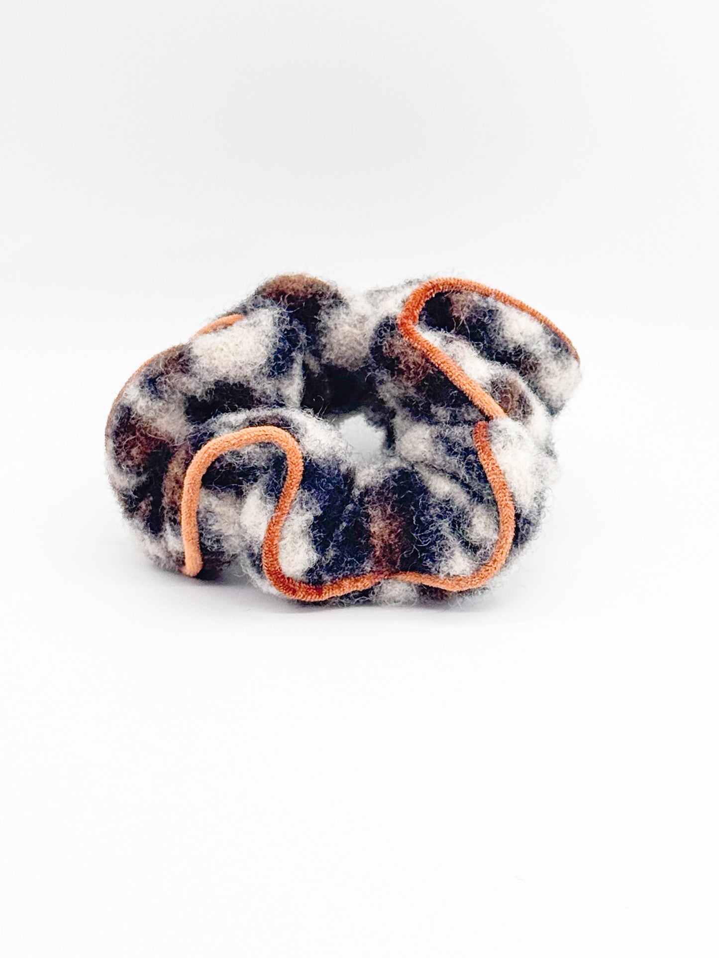 Leopard print scrunchie with orange trim on a white background