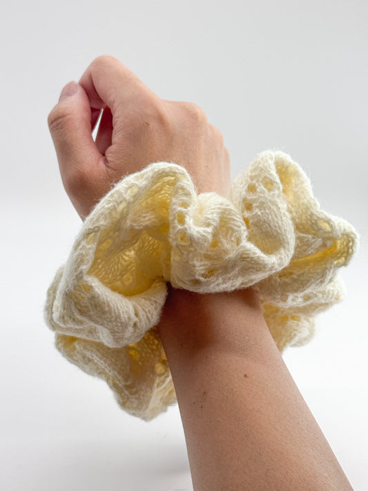White knit scrunchie on wrist against a white background