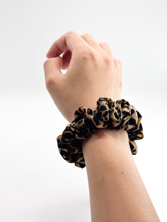 Hand wearing a leopard print scrunchie on a white background