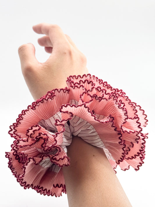 A pink large scrunchie on a wrist white background
