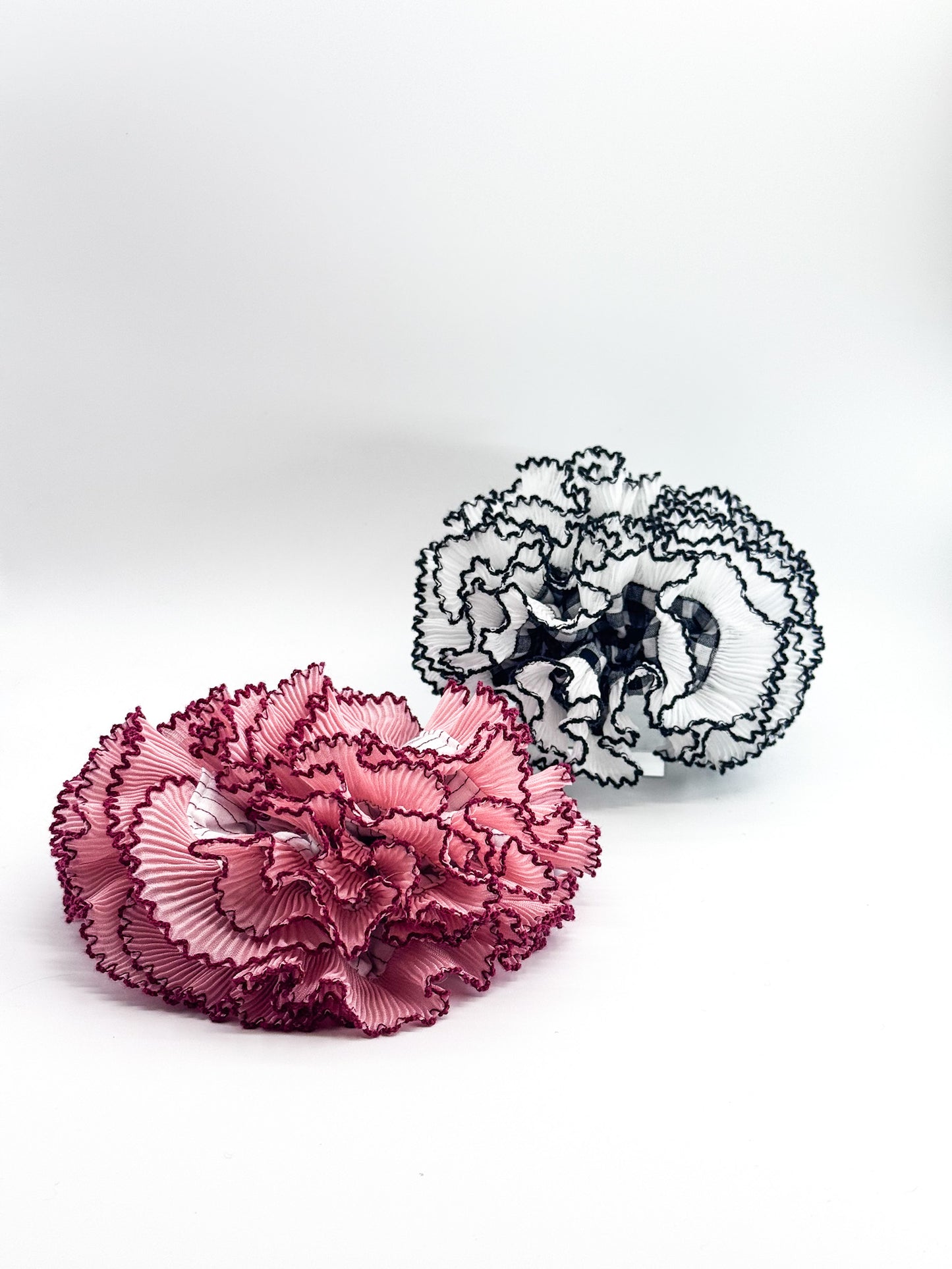 A pink scrunchie and a black and white scrunchie on a white background