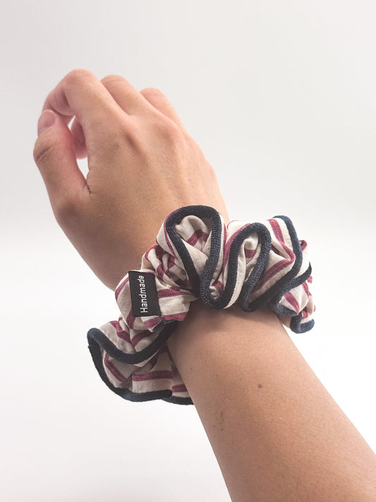 Hand wearing a striped scrunchie on a white background
