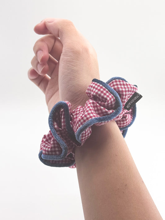 Hand wearing a red and blue checkered scrunchie on a white background