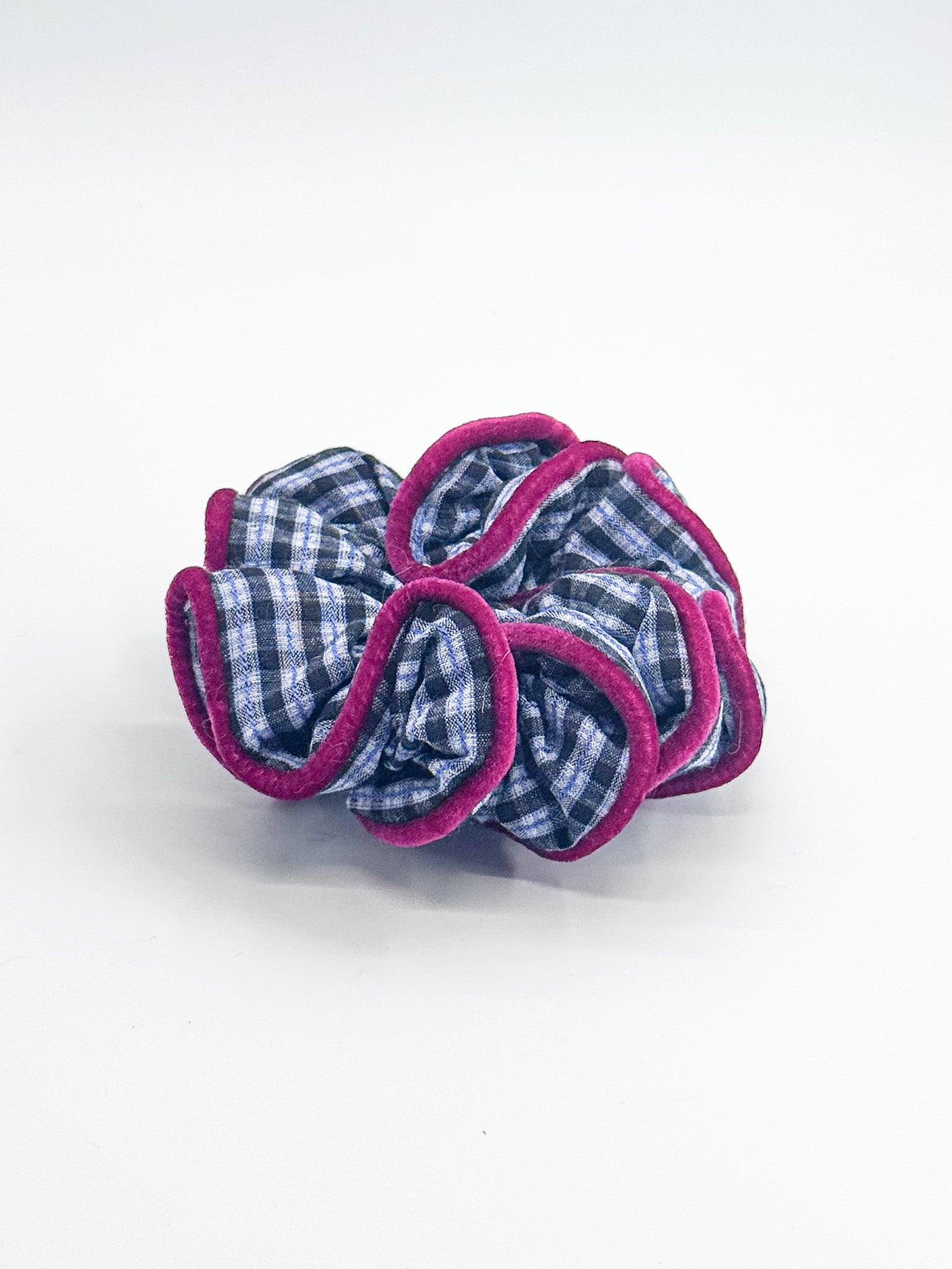 A scrunchie with blue checkered center and pink outer layers on a white background