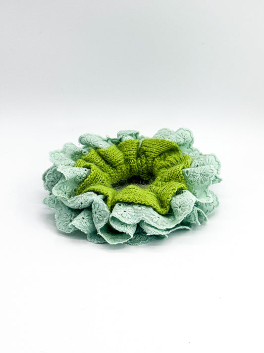 Green knitted large scrunchie with lace trim on a white background