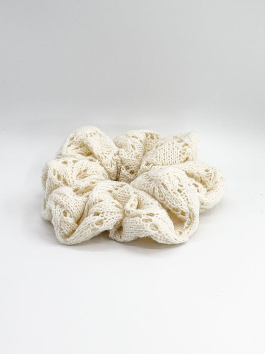 Knitted cream-colored scrunchie on a white background