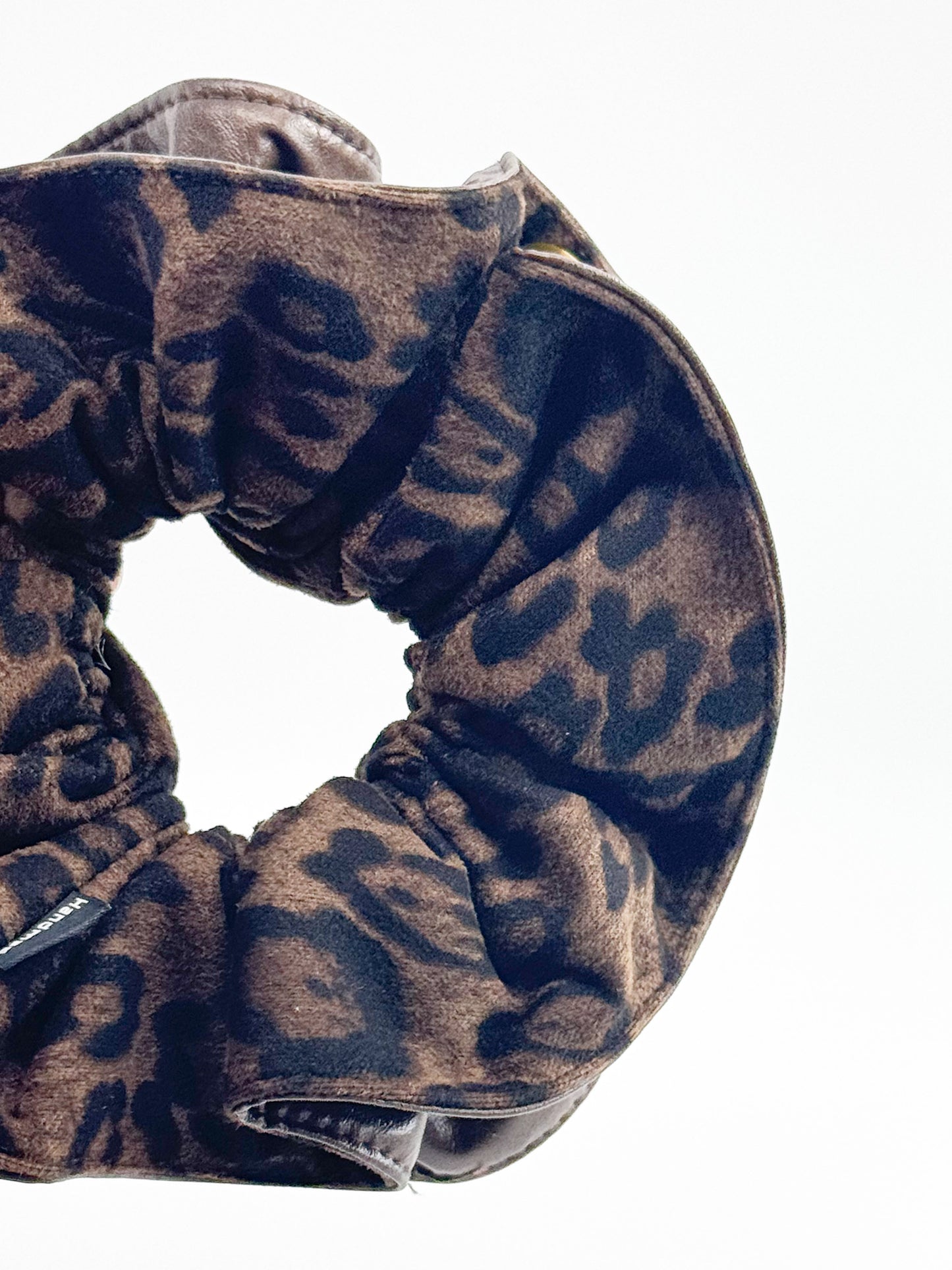 Brown scrunchie with black leopard print pattern on a white background