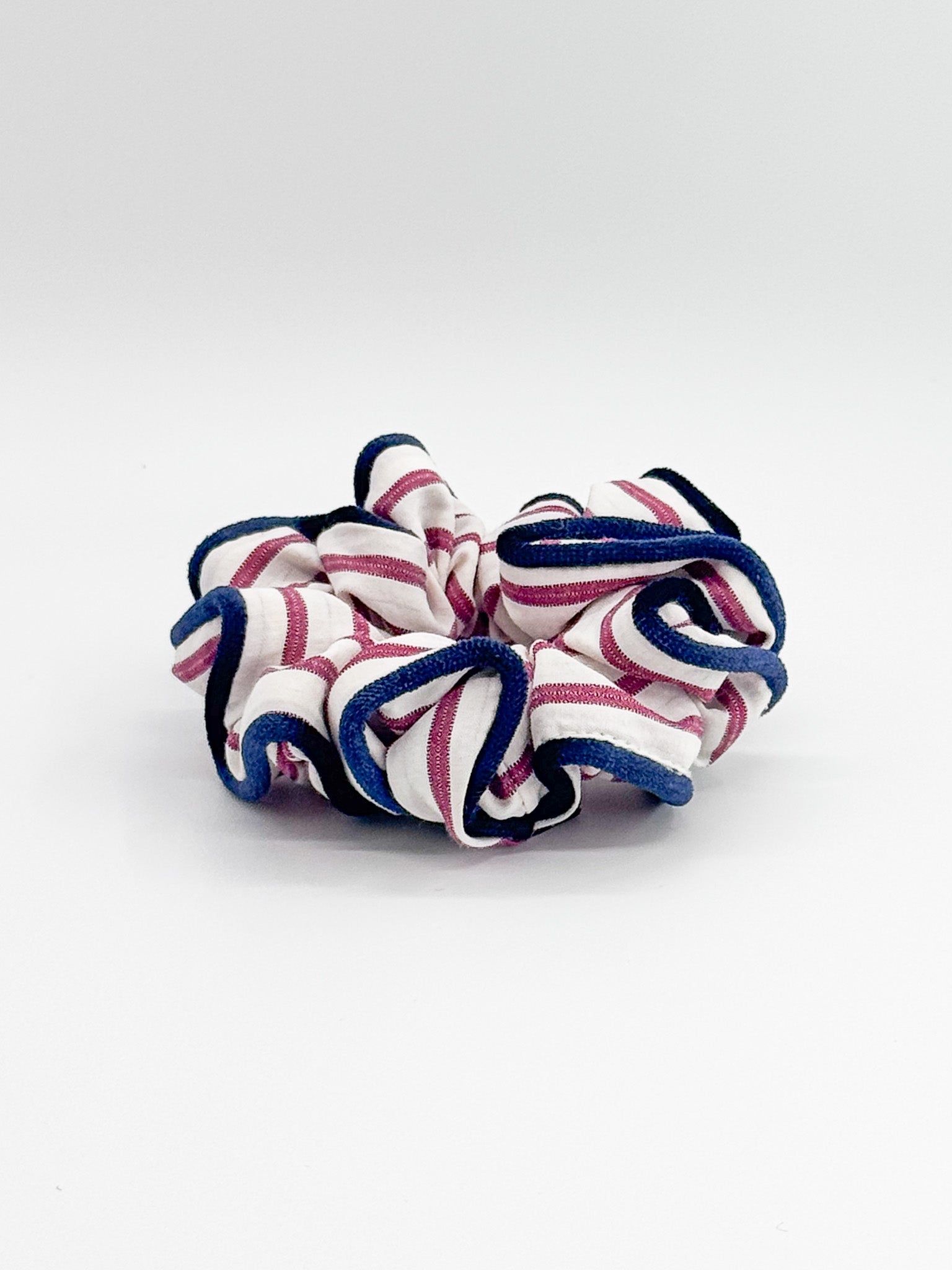 Striped scrunchie with pink and blue pattern on a white background