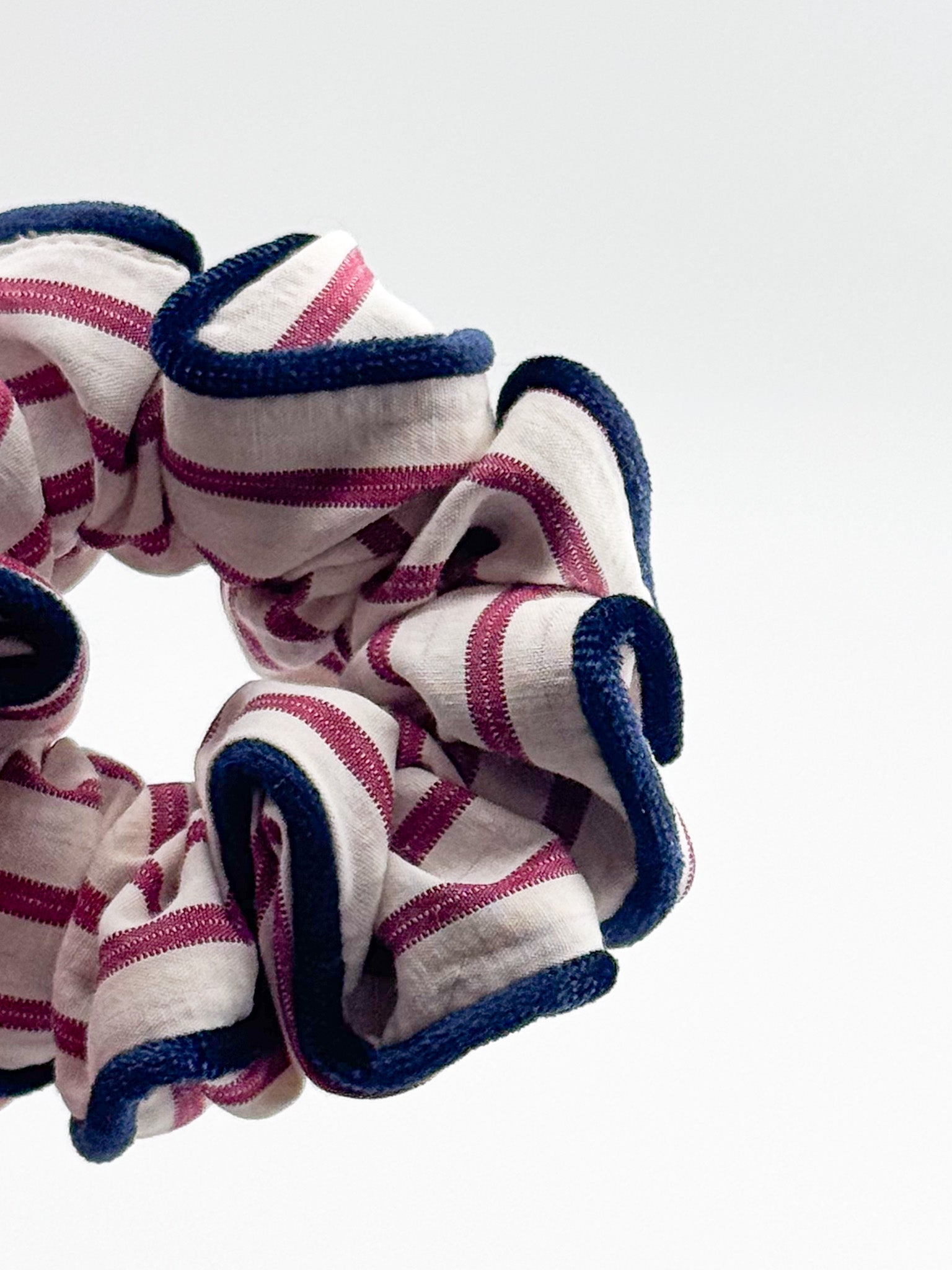 Striped scrunchie with blue and pink pattern on a white background