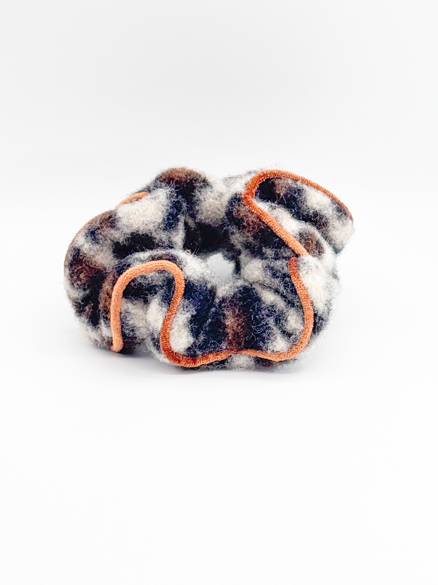 Leopard print scrunchie with orange trim on a white background