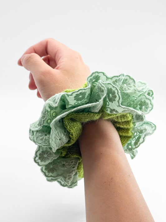 Green scrunchie on a wrist against a white background