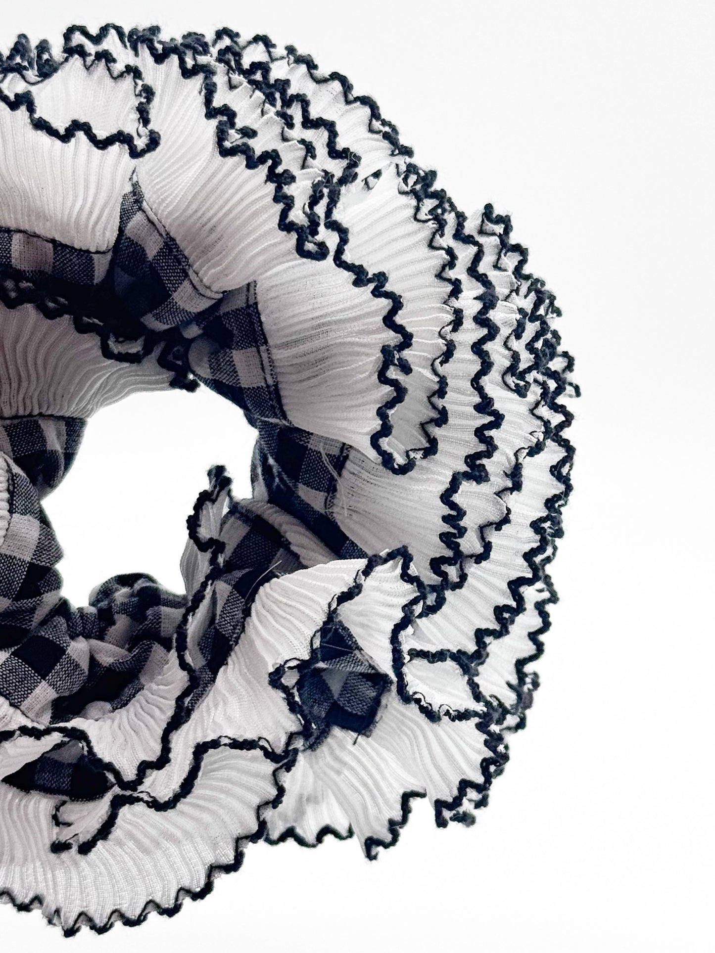 Decorative scrunchie with ruffled white and plaid black and black ribbons on a white background