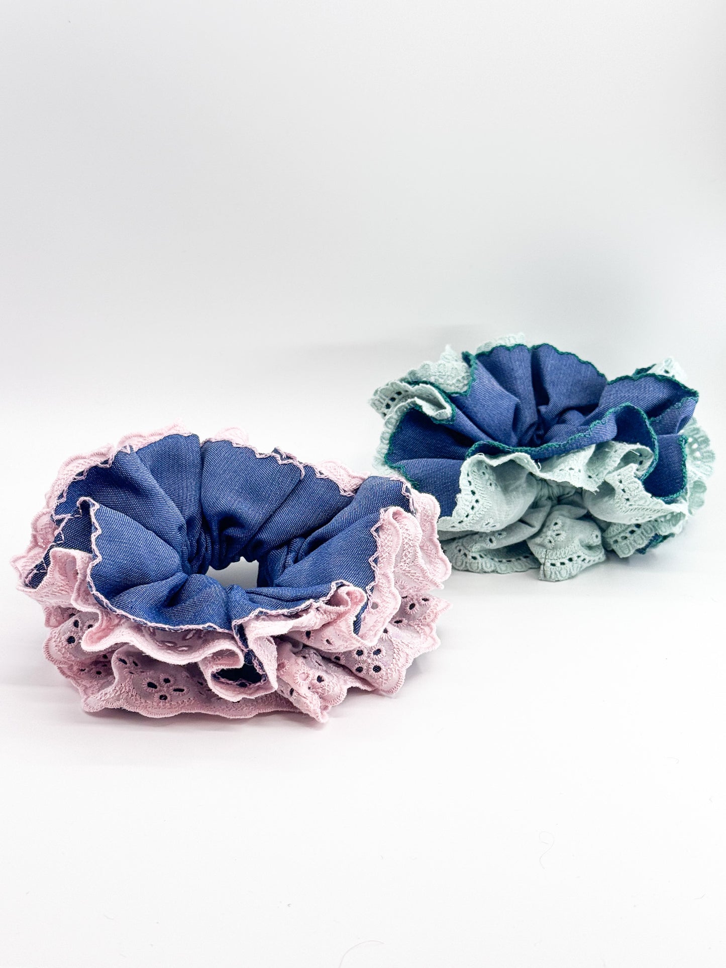 Two fabric scrunchies, one pink and one blue, on a white background