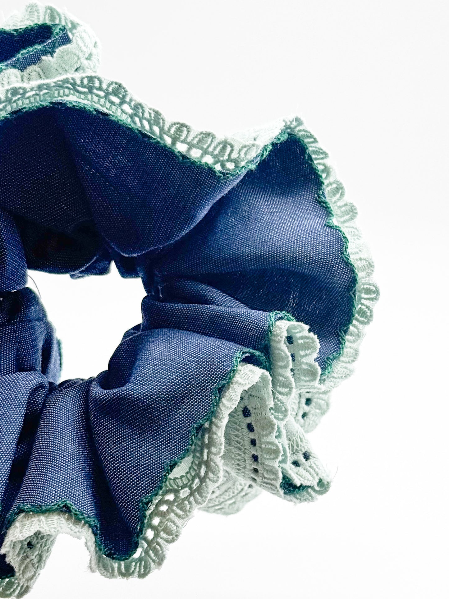 Blue scrunchie with lace detailing on a white background