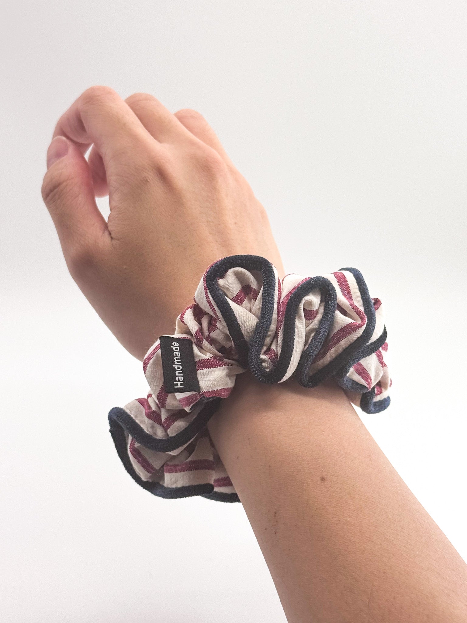 Hand wearing a striped scrunchie on a white background